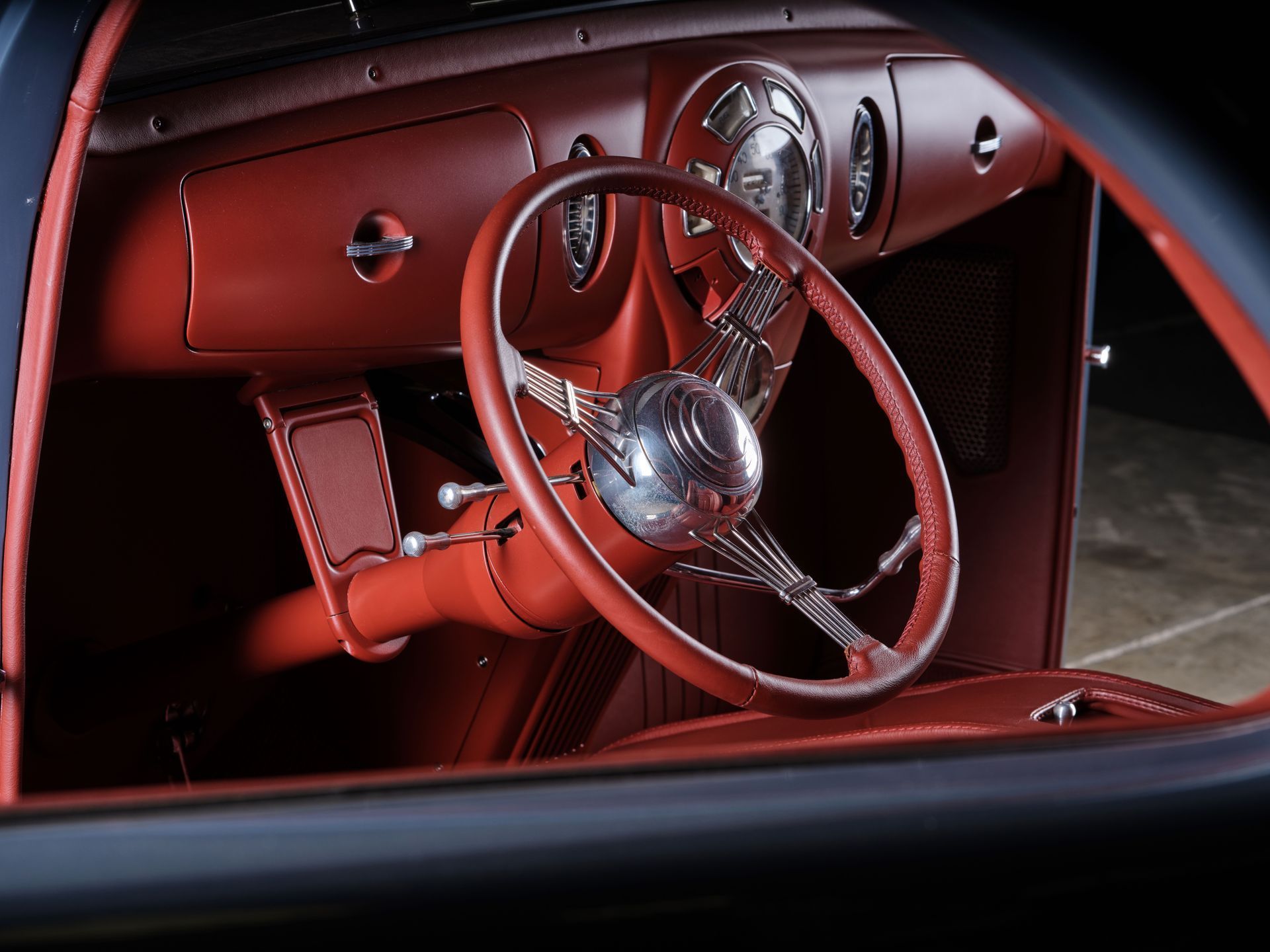 Red vintage car interior with a classic steering wheel and glossy dashboard