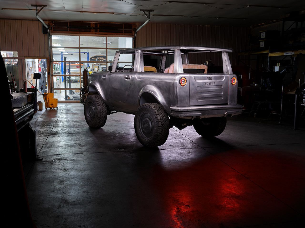 Silver off-road SUV inside a dim garage, with red reflections on the floor.