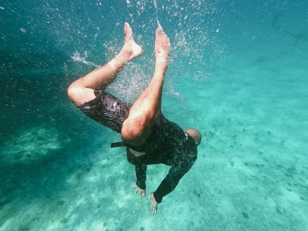 A man is swimming underwater in the ocean.