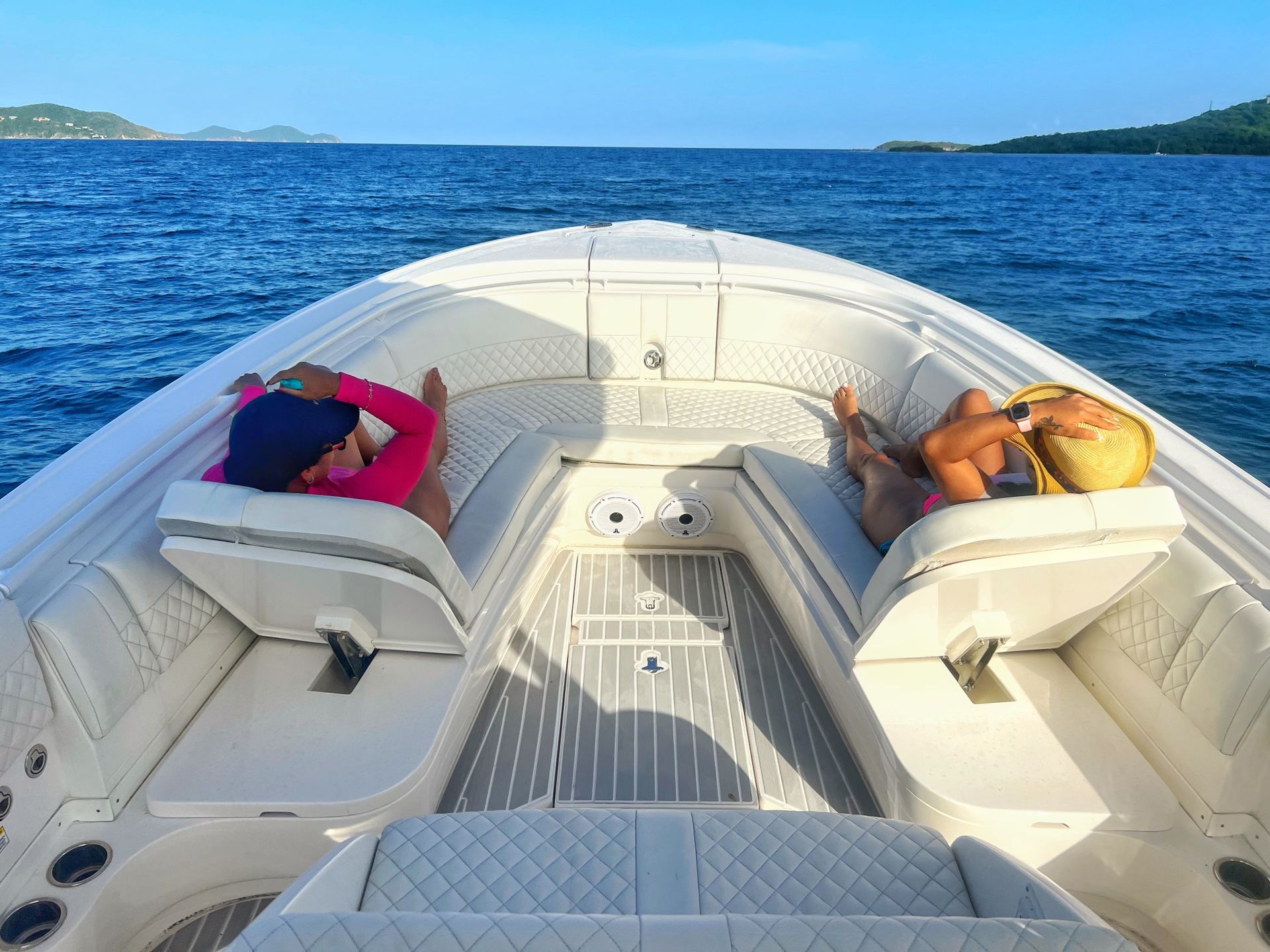 Two people are sitting on the front of a boat in the ocean.