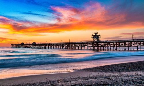 Woman holding hands with a young girl on a couch, indoors, offering support and empathy.