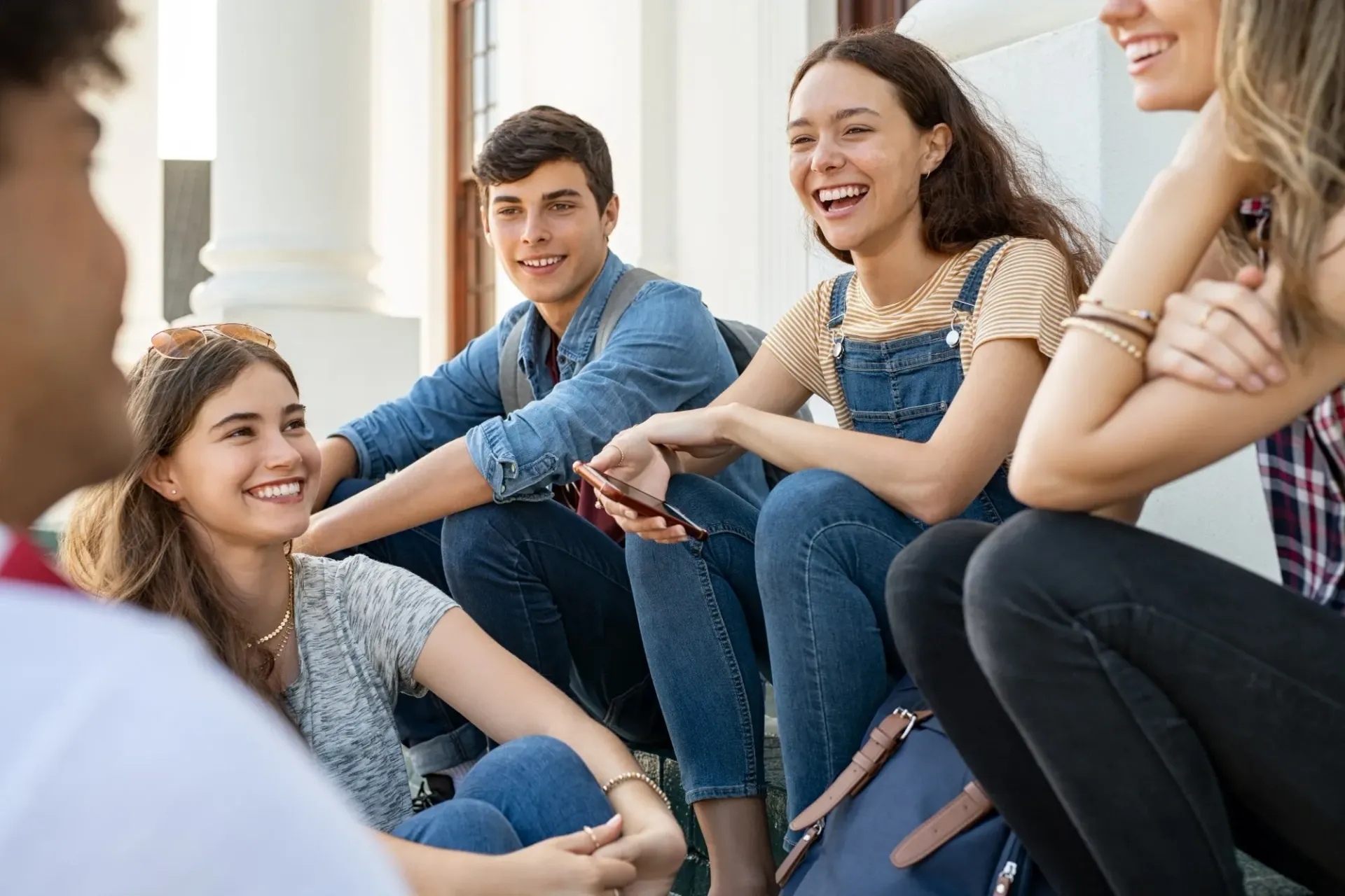 Group of smiling people sitting outdoors, chatting.
