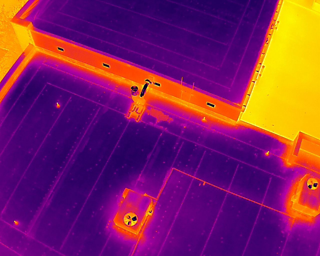 An aerial view of a building with a lot of solar panels on the roof.
