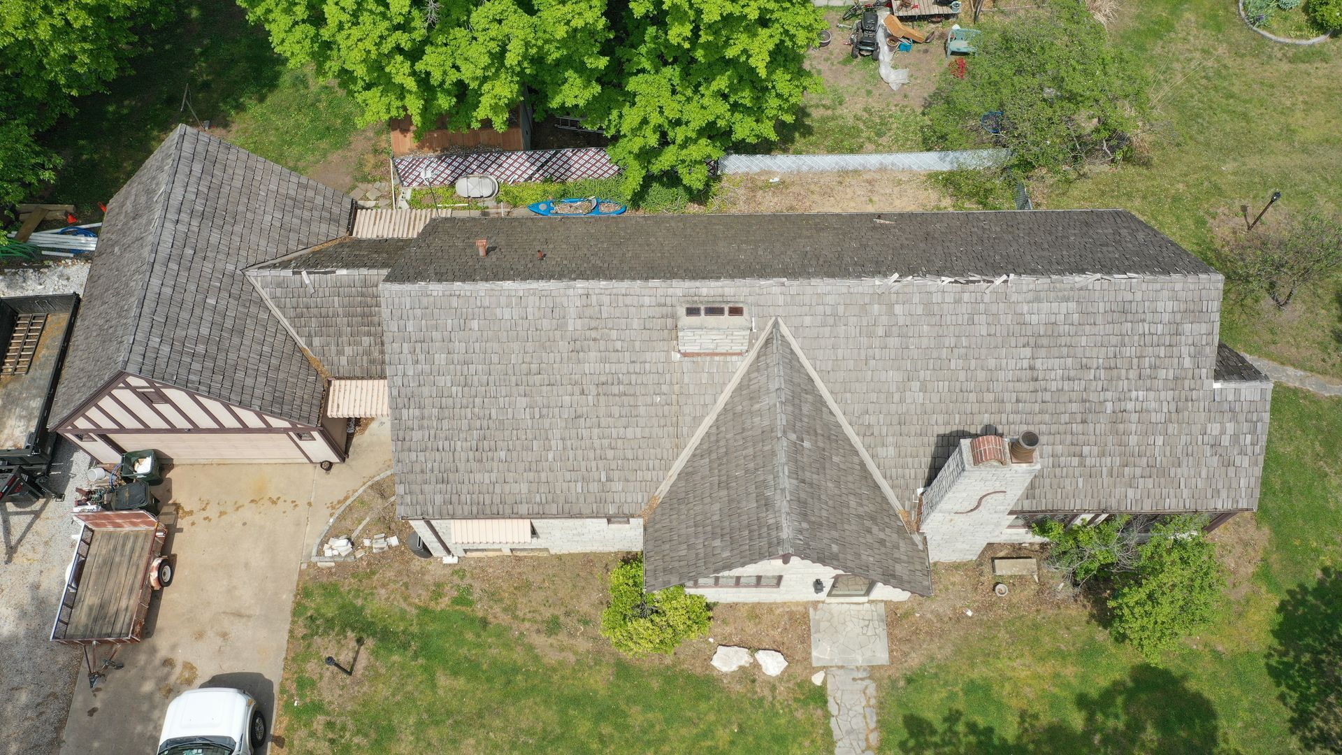 Aerial view of a house with a wood shingle roof, chimney, and attached garage. 