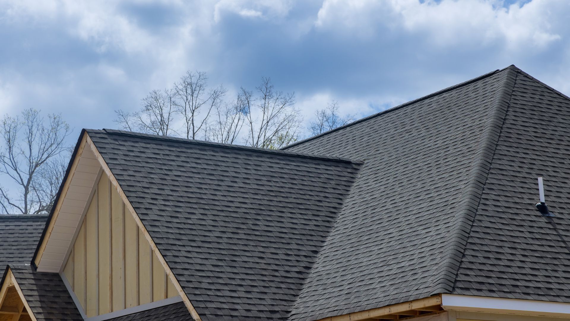 A close up of a roof of a house with a blue sky in the background.