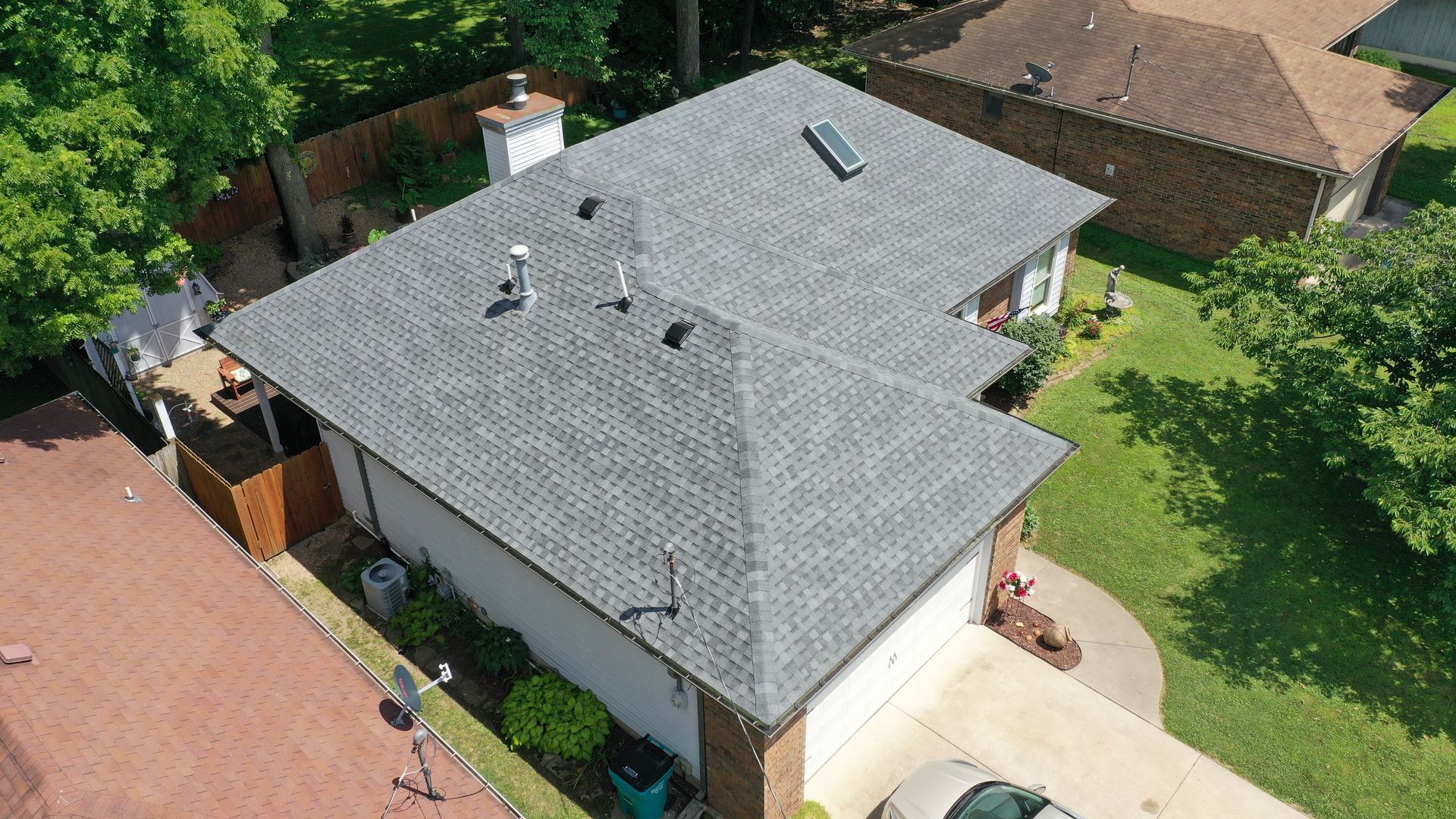An aerial view of a house with a new roof and a car parked in front of it.