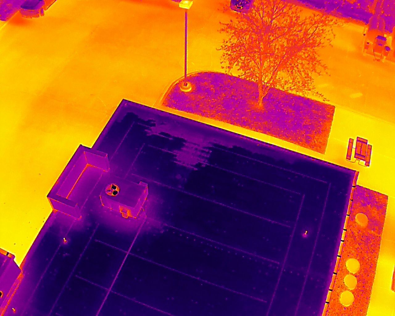 An aerial view of a building with a lot of solar panels on the roof.