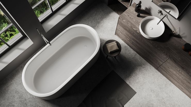 A high-angle view of a modern bathroom with a white oval freestanding bathtub and a circular vessel sink on a wood vanity.