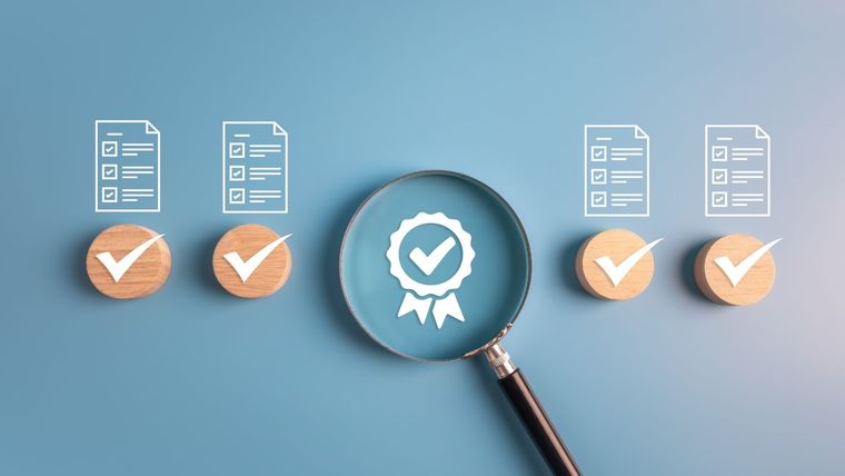 Magnifying glass over a quality assurance badge, flanked by four document icons on wooden discs with checkmarks.