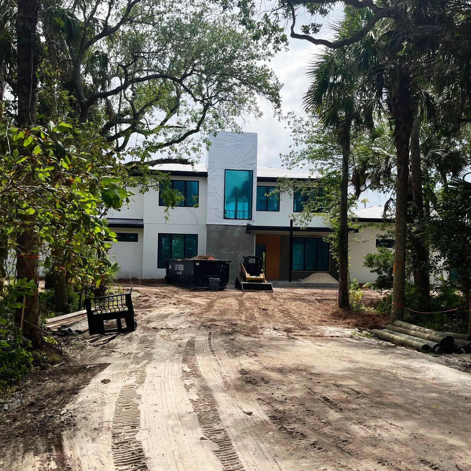 A dirt road leading to a house with a bulldozer parked in front of it