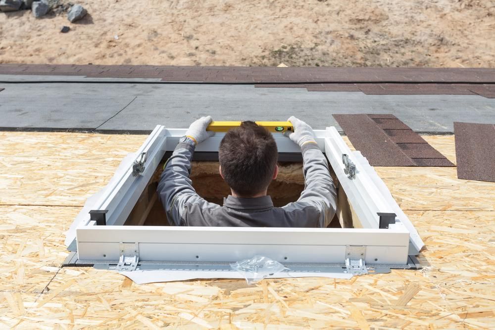 A Man Is Measuring a Skylight with A Tape Measure — Bradley Roofing in Tuncurry, NSW