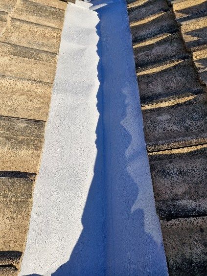 White waterproof membrane placed on a blue painted roof valley on a tile roof. — Bradley Roofing in Tuncurry, NSW