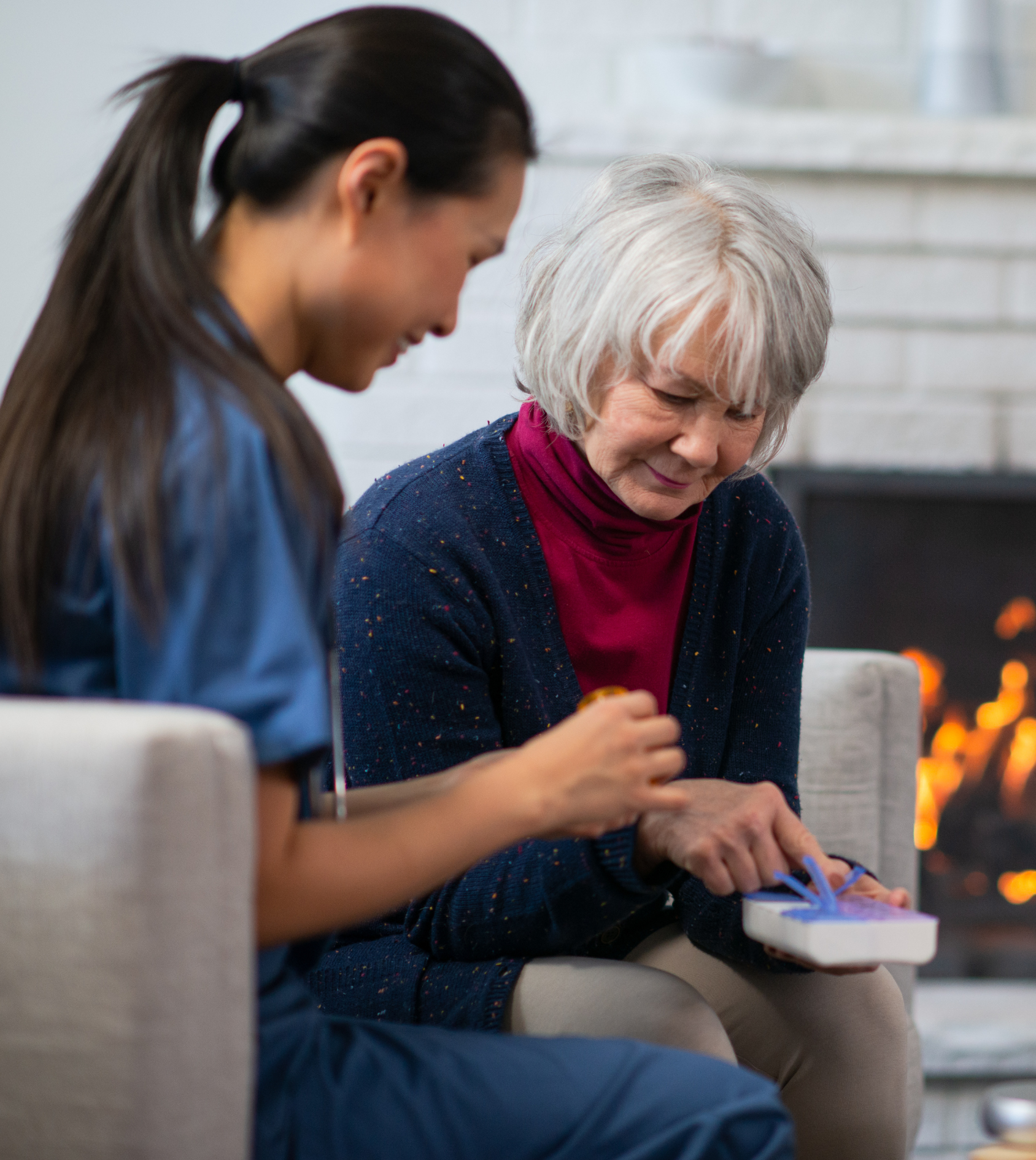 An elderly woman is sitting on a couch talking to a nurse.
