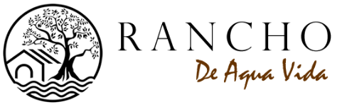 Logo for Rancho De Agua Vida: a round emblem with a tree, house, and water, with the words 