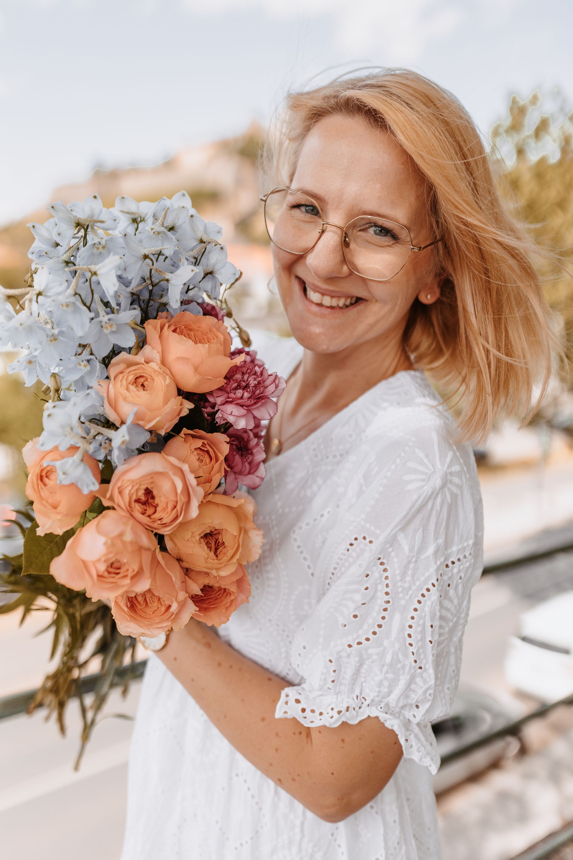 A woman in a white dress is holding a bouquet of flowers.