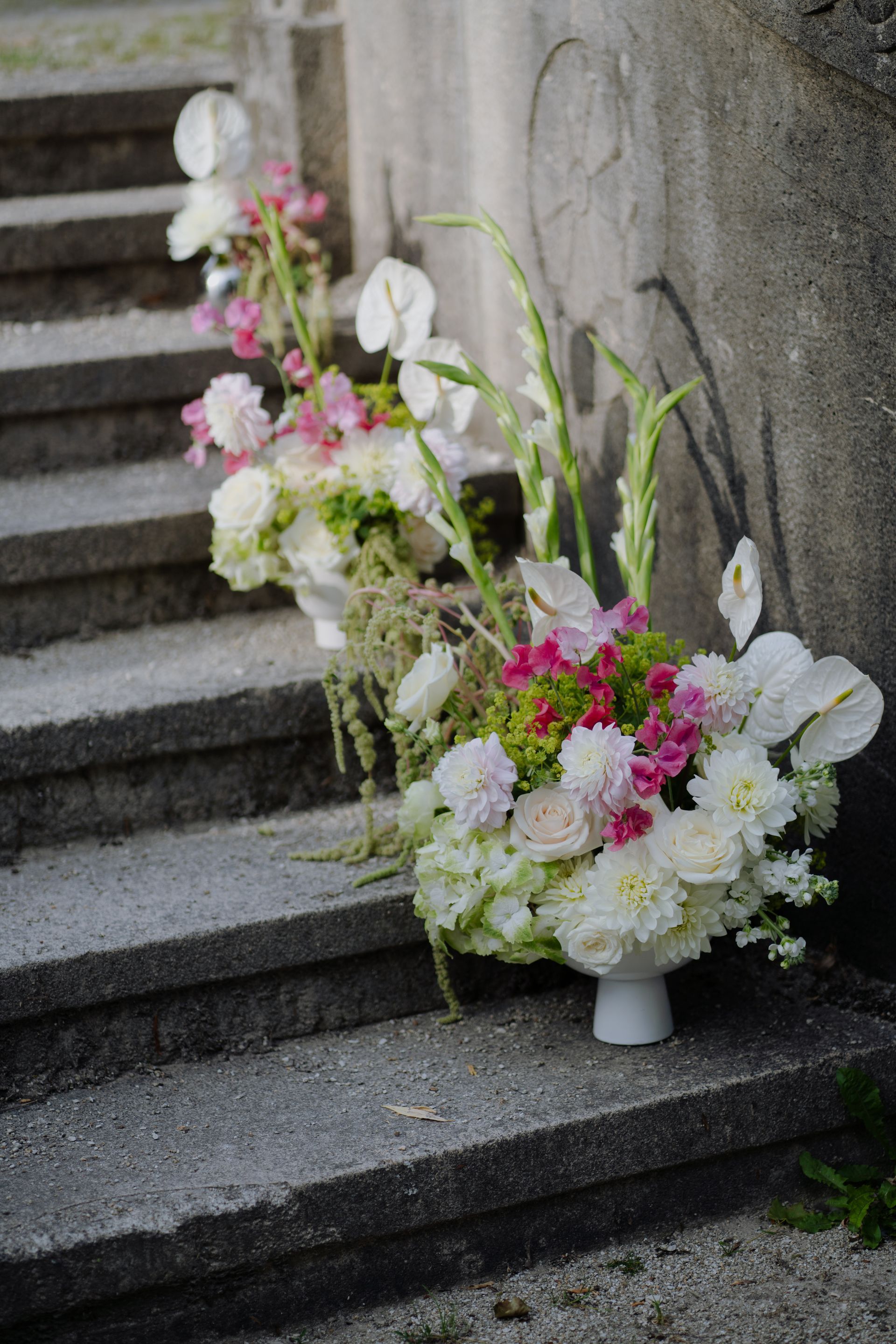 A vase filled with flowers is sitting on a set of stairs.