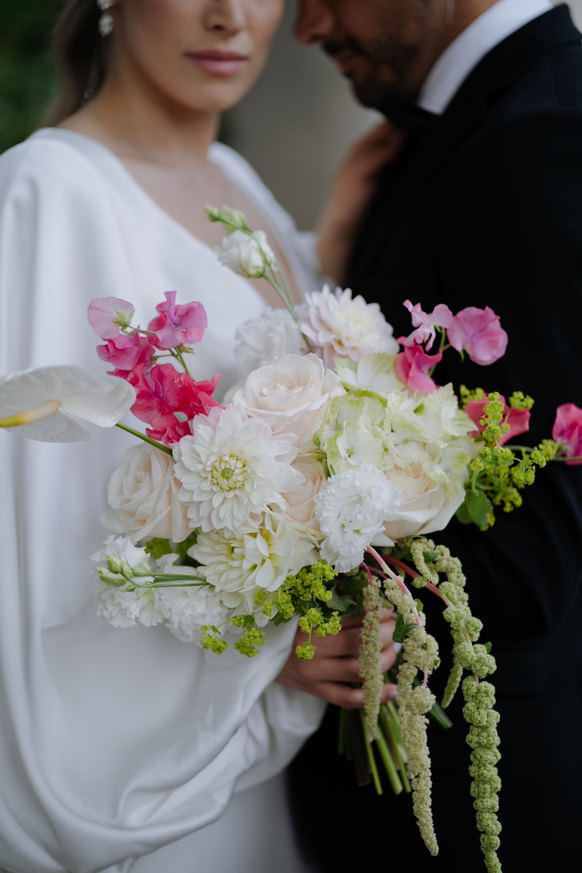 A bride and groom are posing for a picture while the bride is holding a bouquet of flowers.