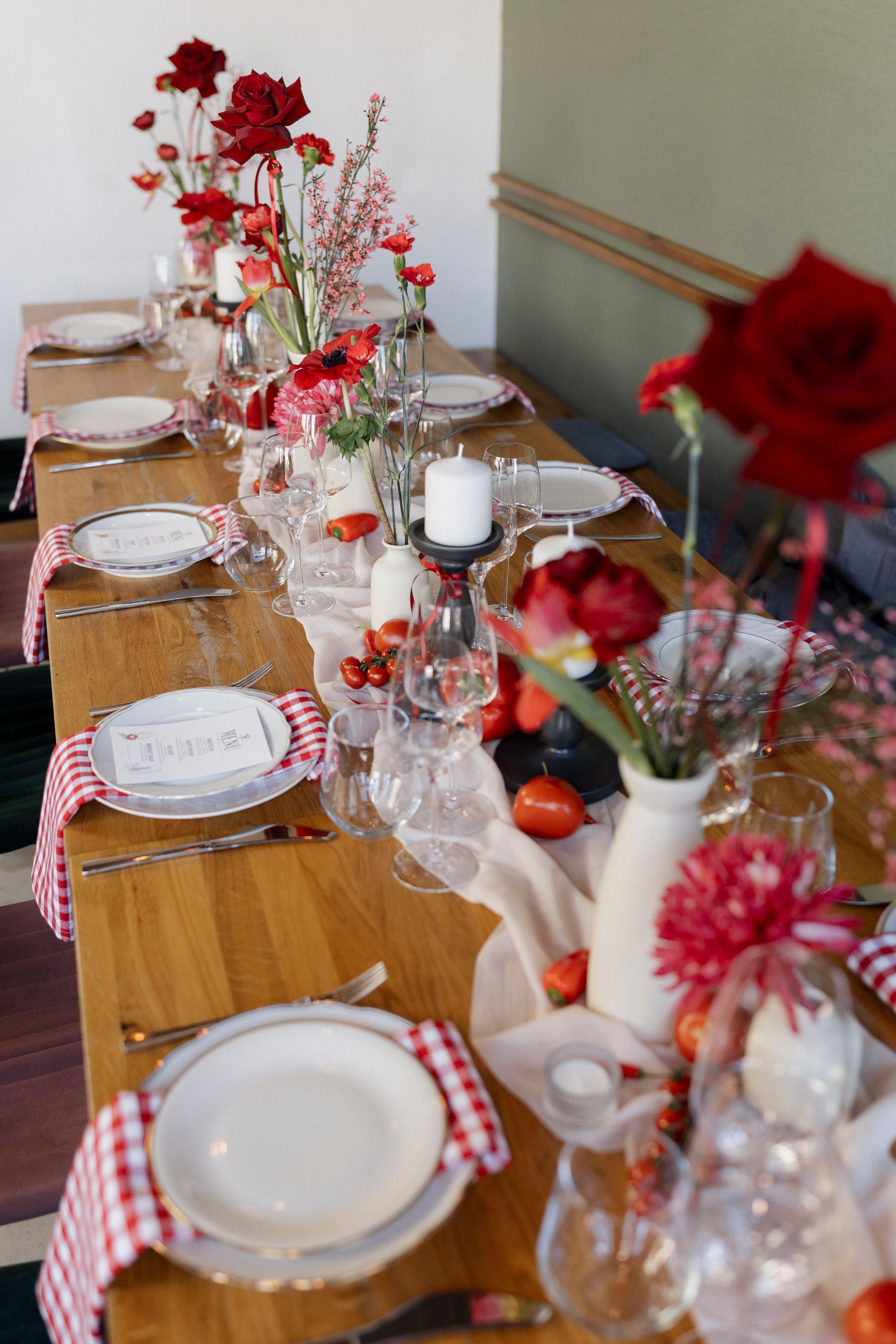 A long wooden table with plates , candles , and flowers on it.