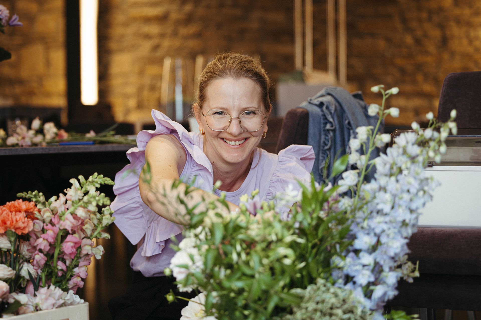 A woman is smiling while holding a bouquet of flowers.