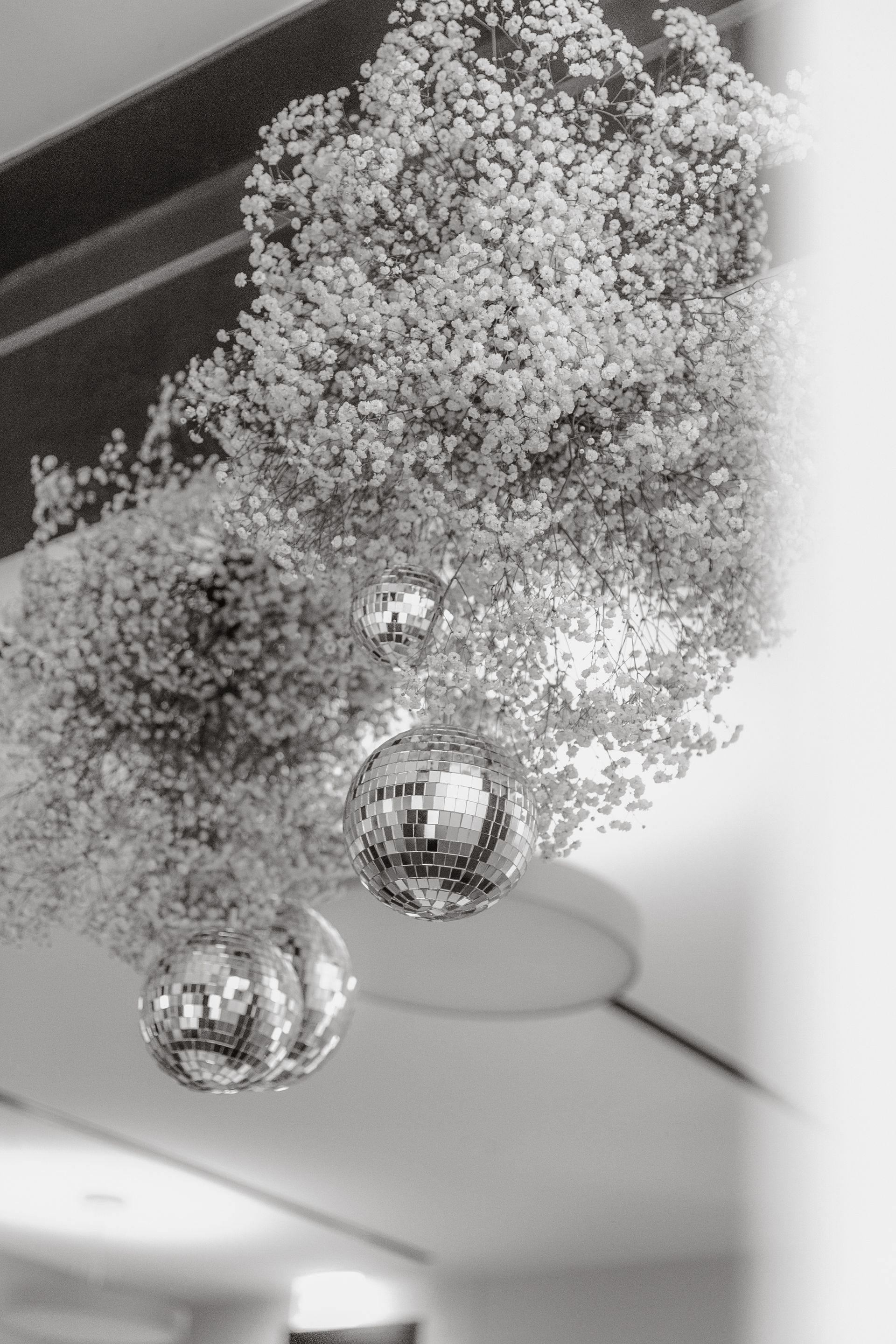 A black and white photo of flowers and disco balls hanging from the ceiling.