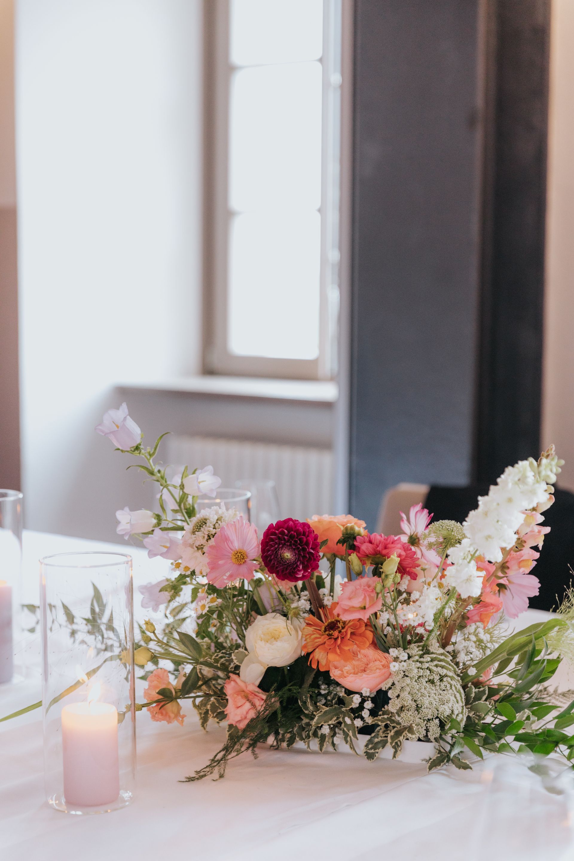 A table with a vase of flowers and candles on it.
