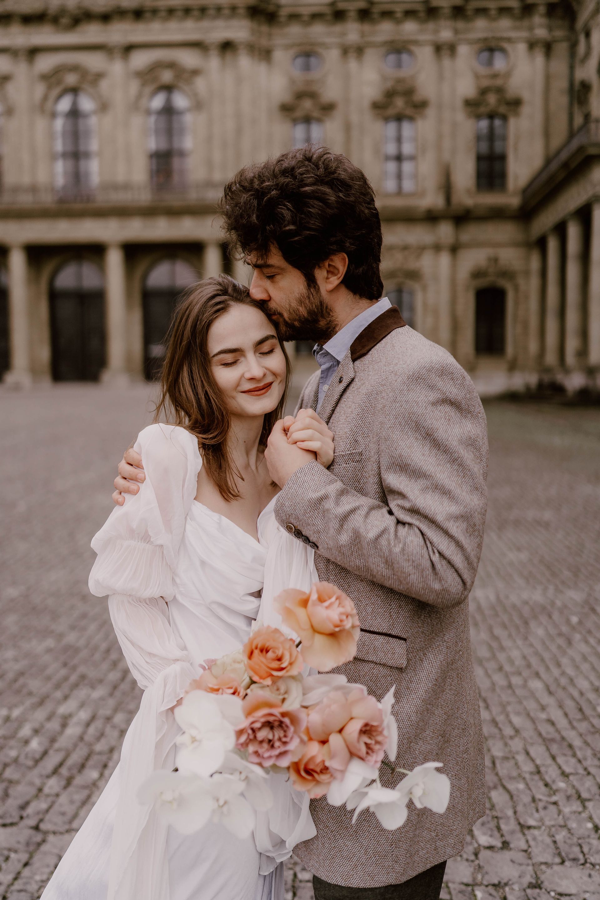 A bride and groom are posing for a picture in front of a building.
