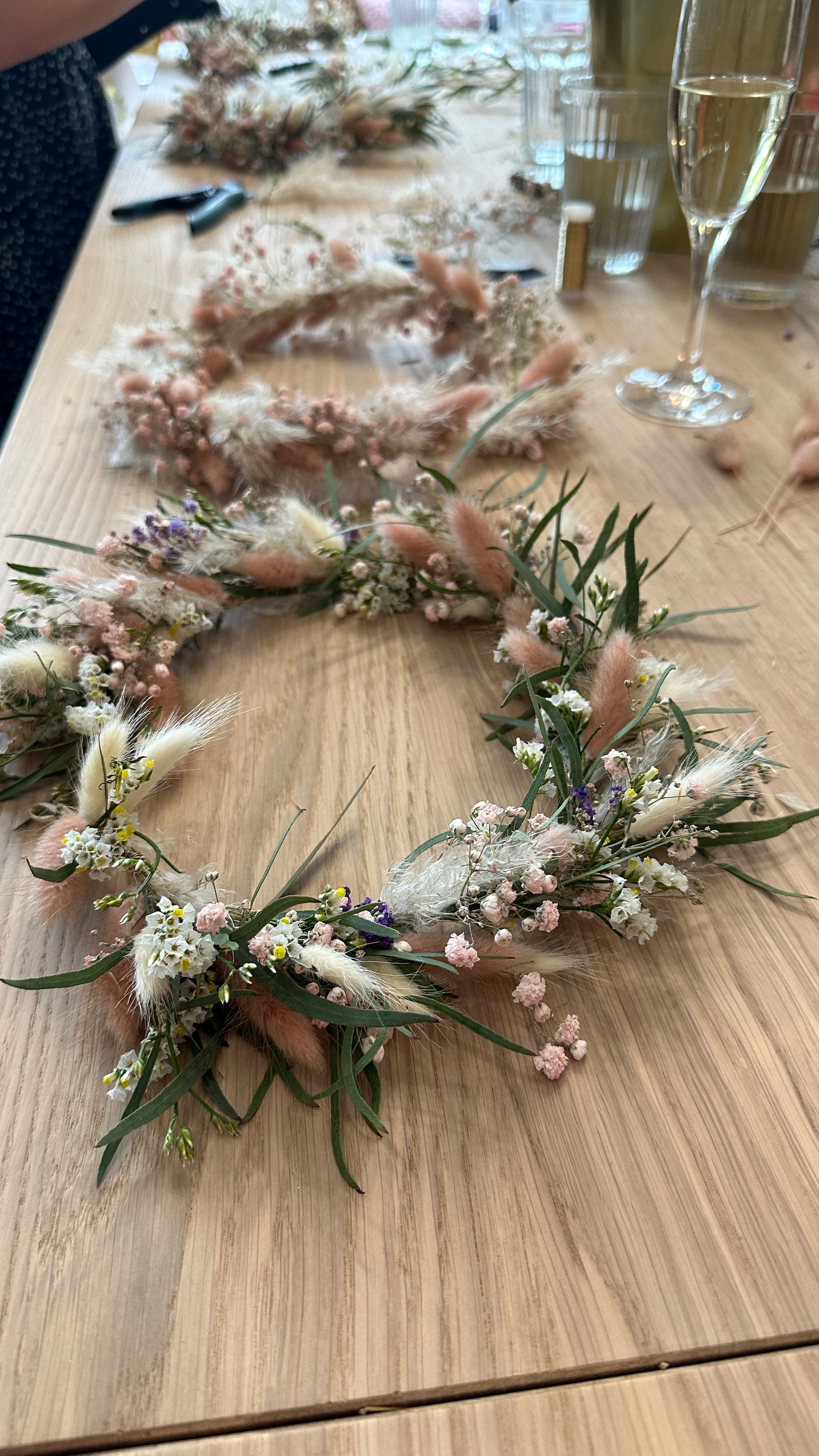 A wreath of dried flowers is sitting on a wooden table.