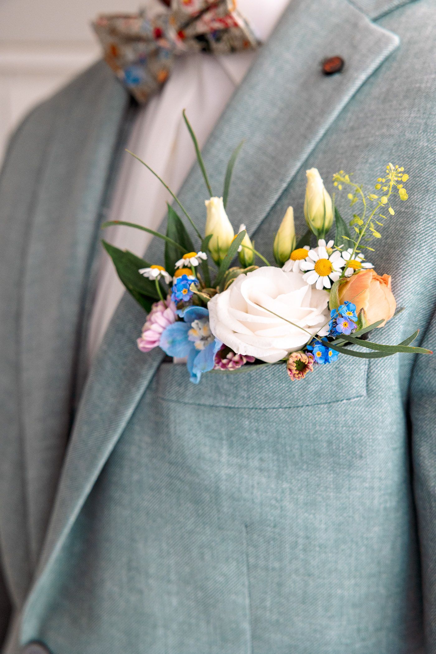 A man in a suit and bow tie has flowers in his pocket.