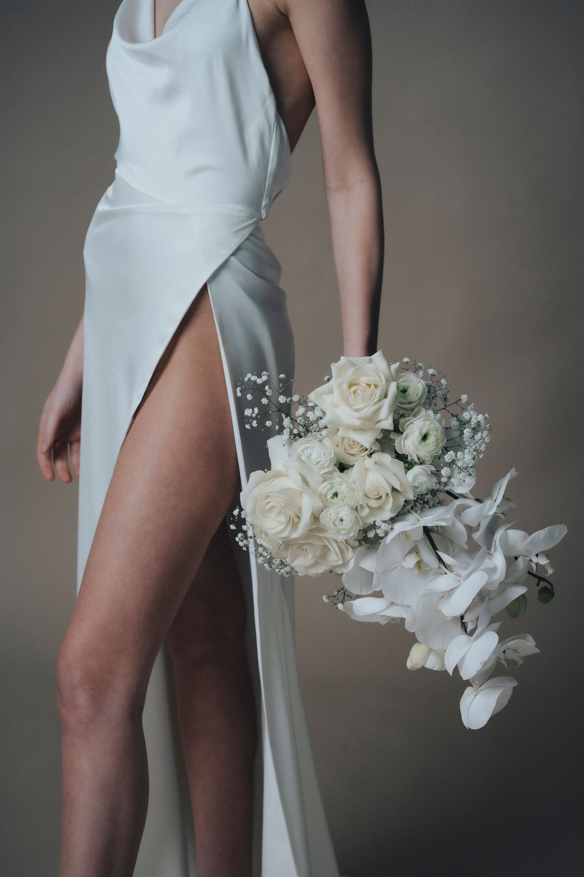 A woman in a white dress is holding a bouquet of white flowers.