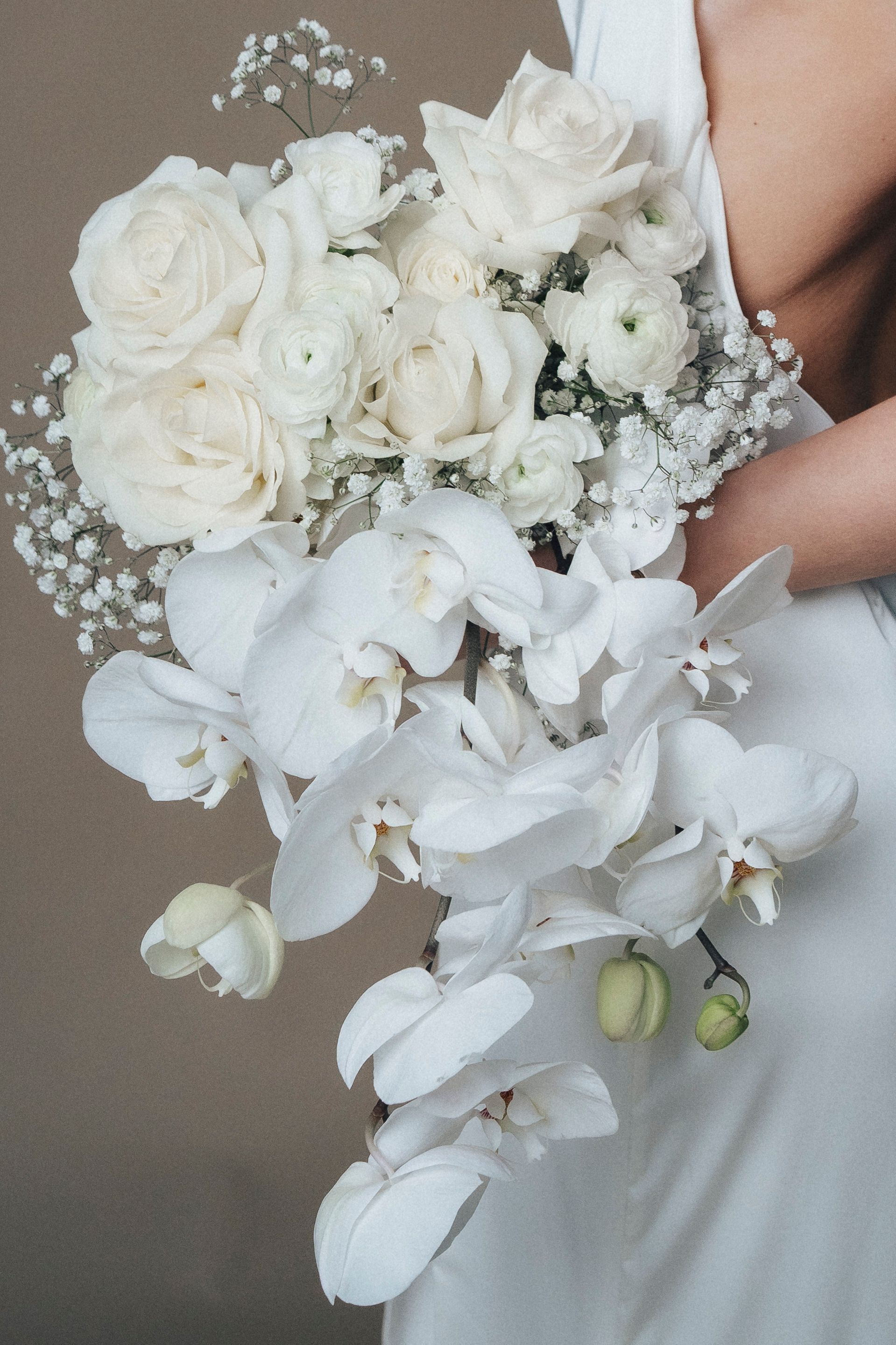 A woman in a white dress is holding a bouquet of white flowers