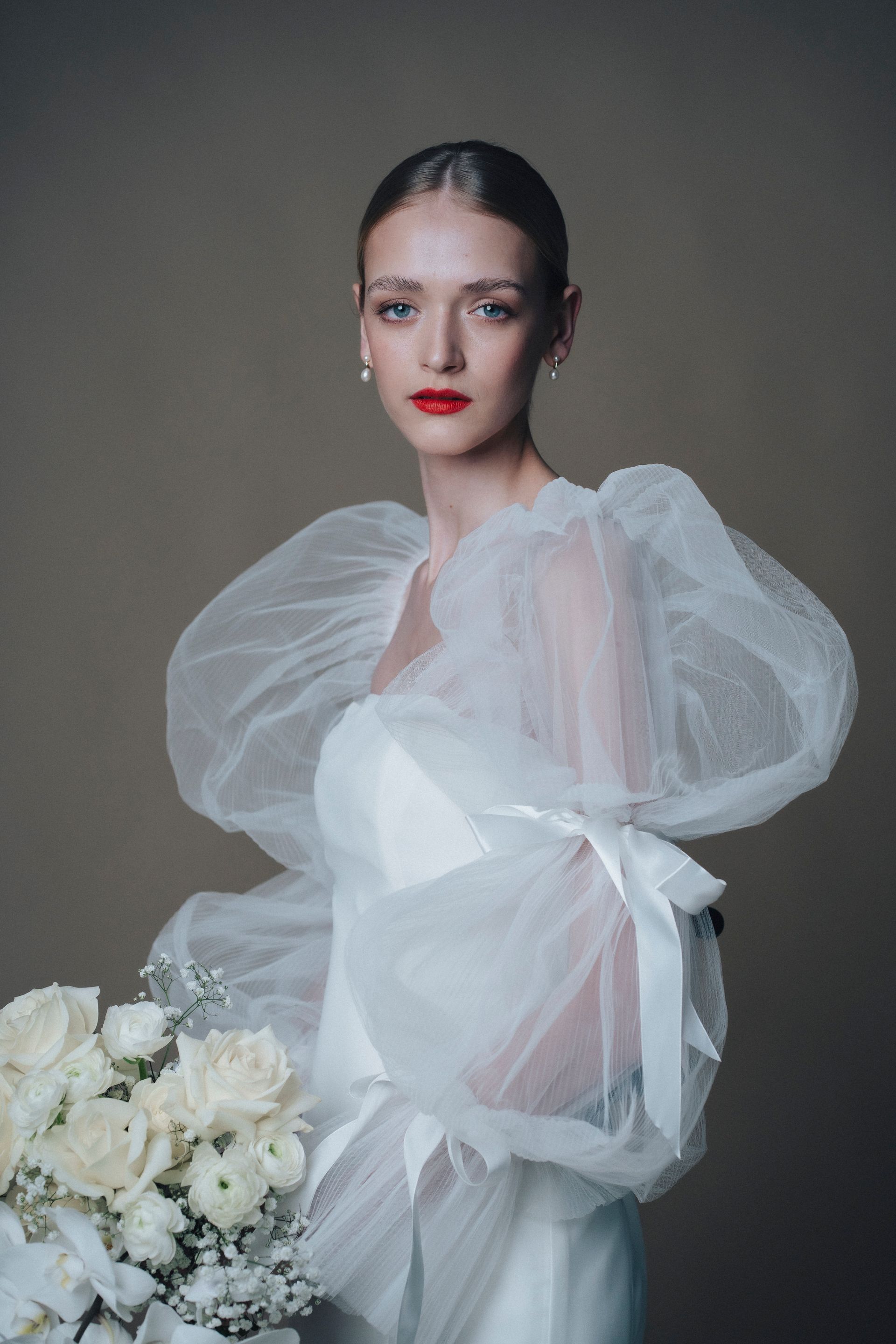 A woman in a white dress is holding a bouquet of white flowers.