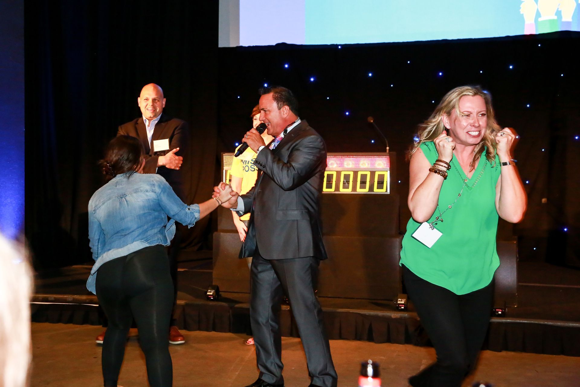 A group of people are dancing on a stage while a man sings into a microphone.