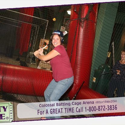 A woman is swinging a bat in a colossal batting cage arena