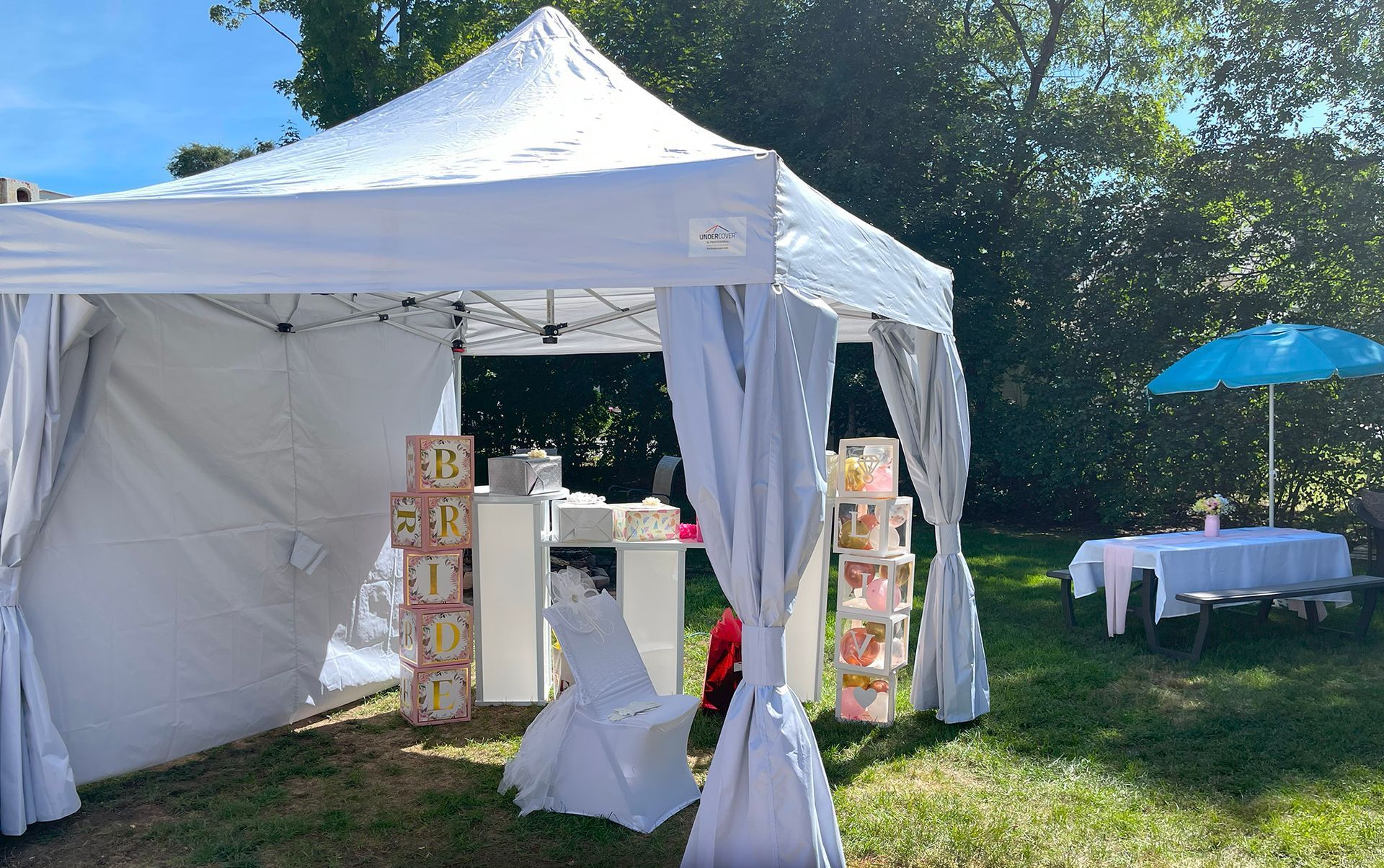 A white tent is sitting in the middle of a grassy field.