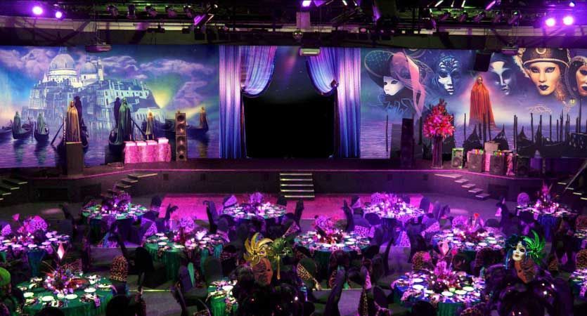A large room filled with tables and chairs and purple lights.