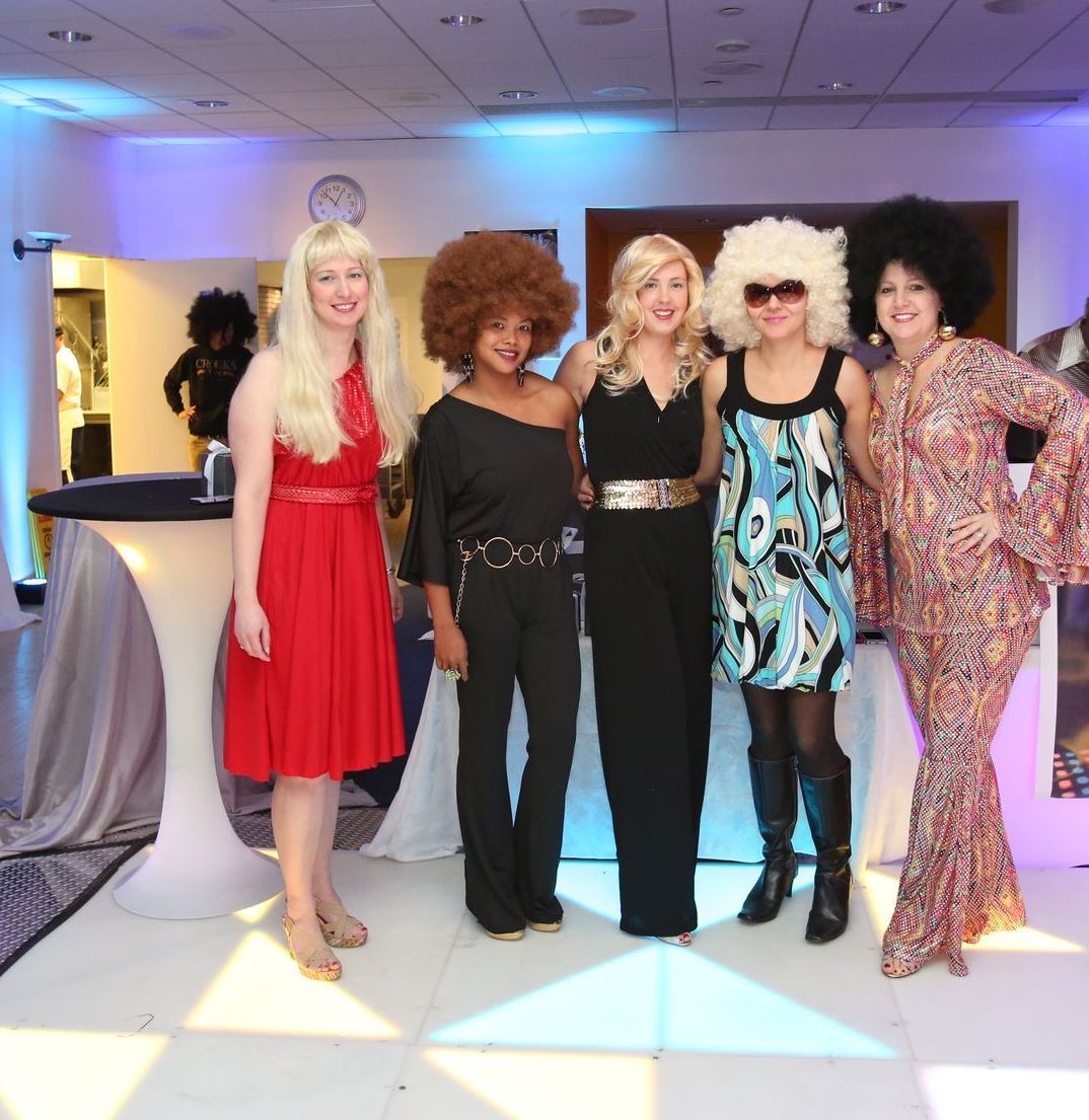 A group of women posing for a picture with one wearing a red dress