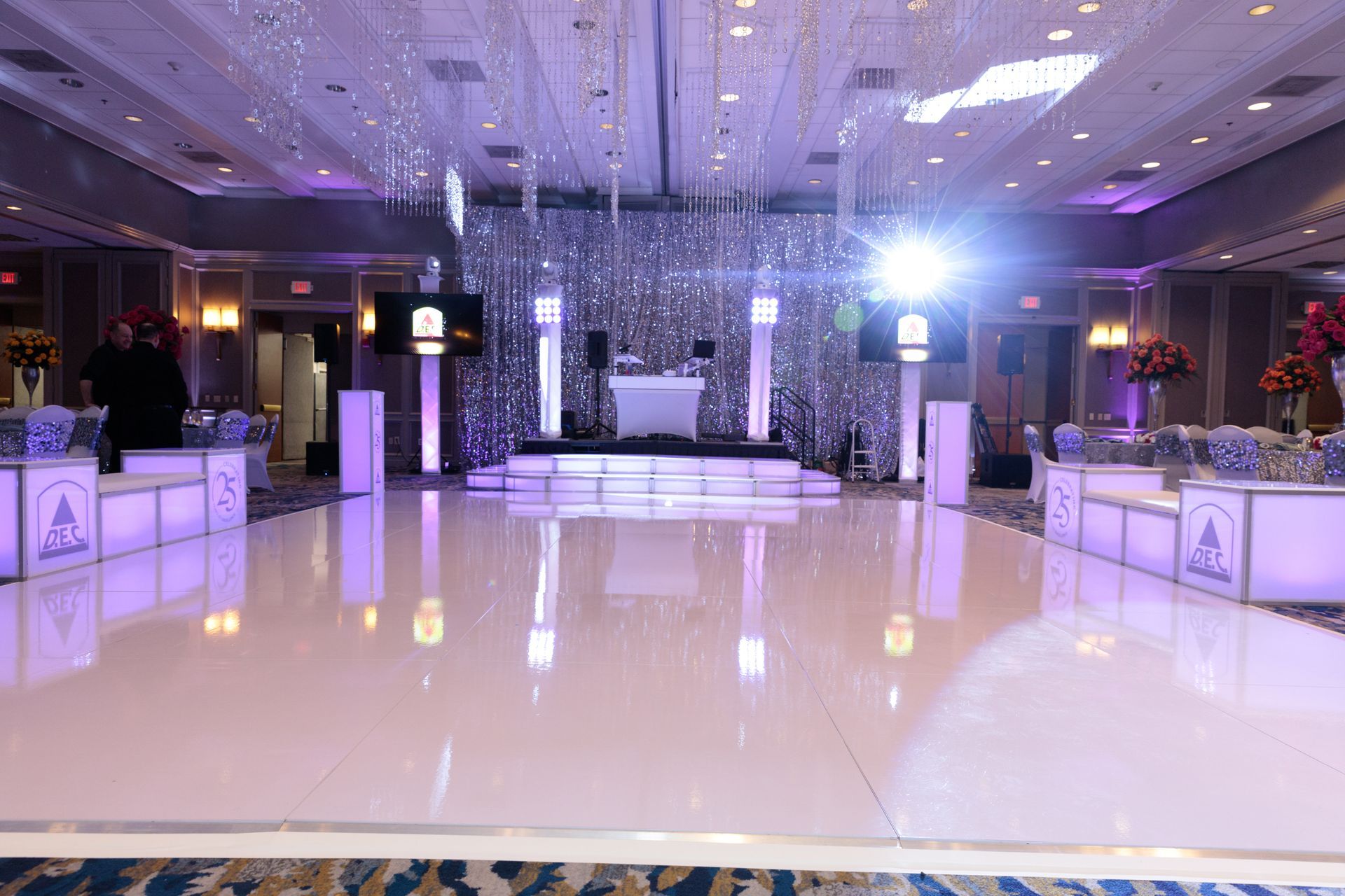 A large room with a white dance floor and purple lights.
