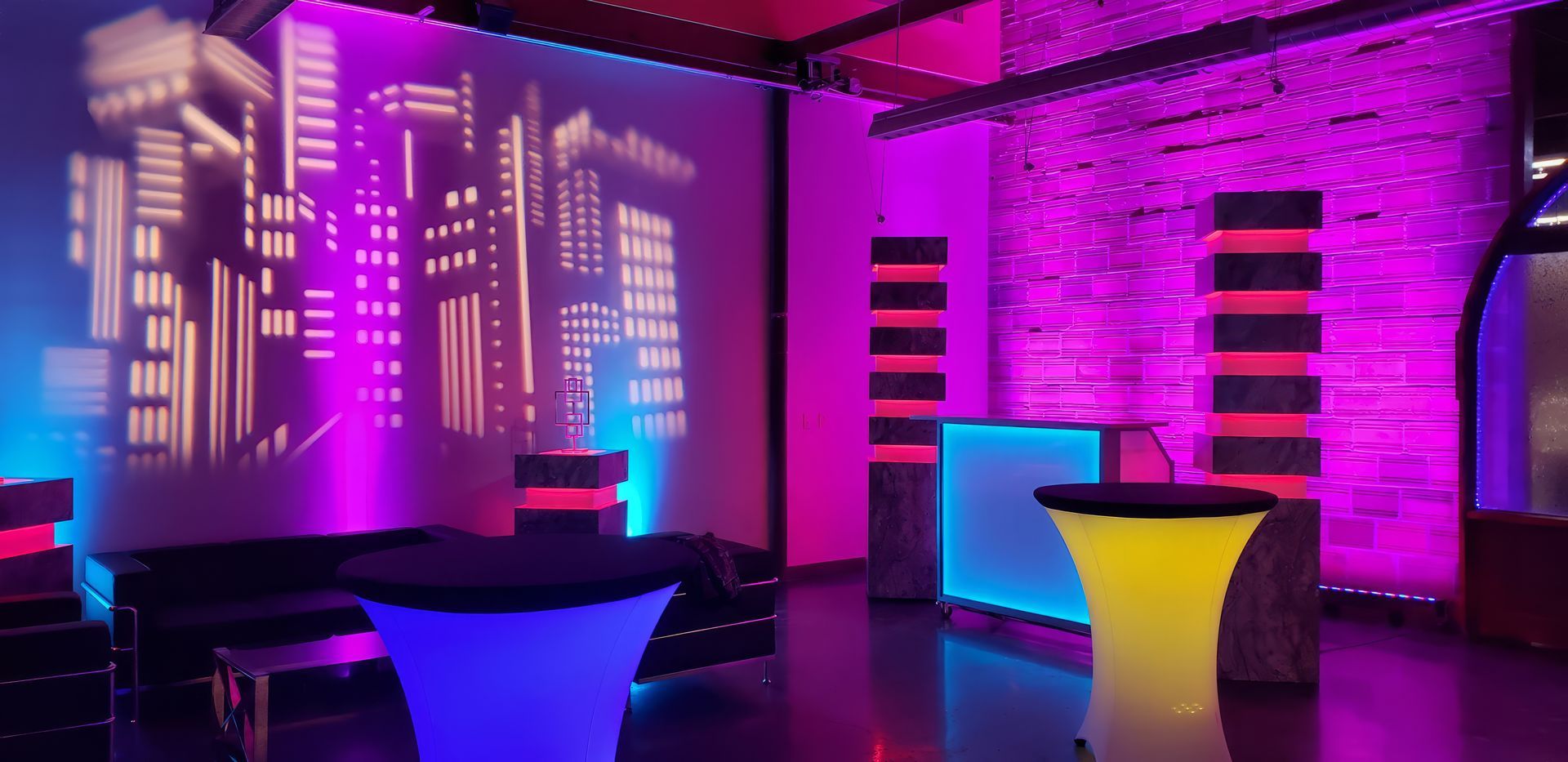 A room with tables and a wall with a city skyline projected on it.