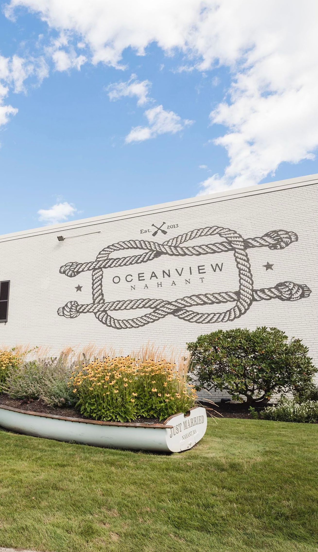 A large piece of wood is sitting in the grass in front of a building.