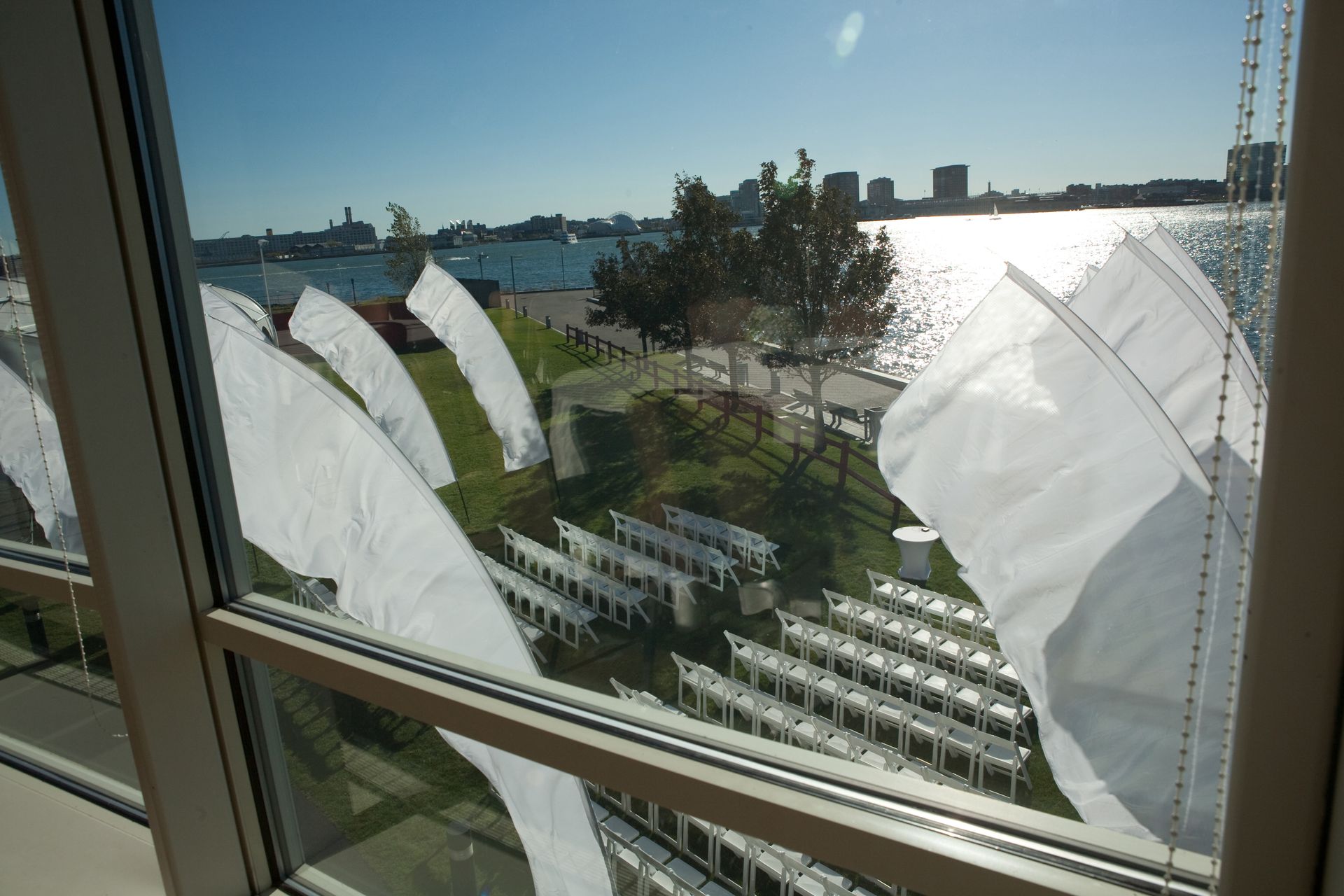 A row of white chairs are lined up in front of a body of water