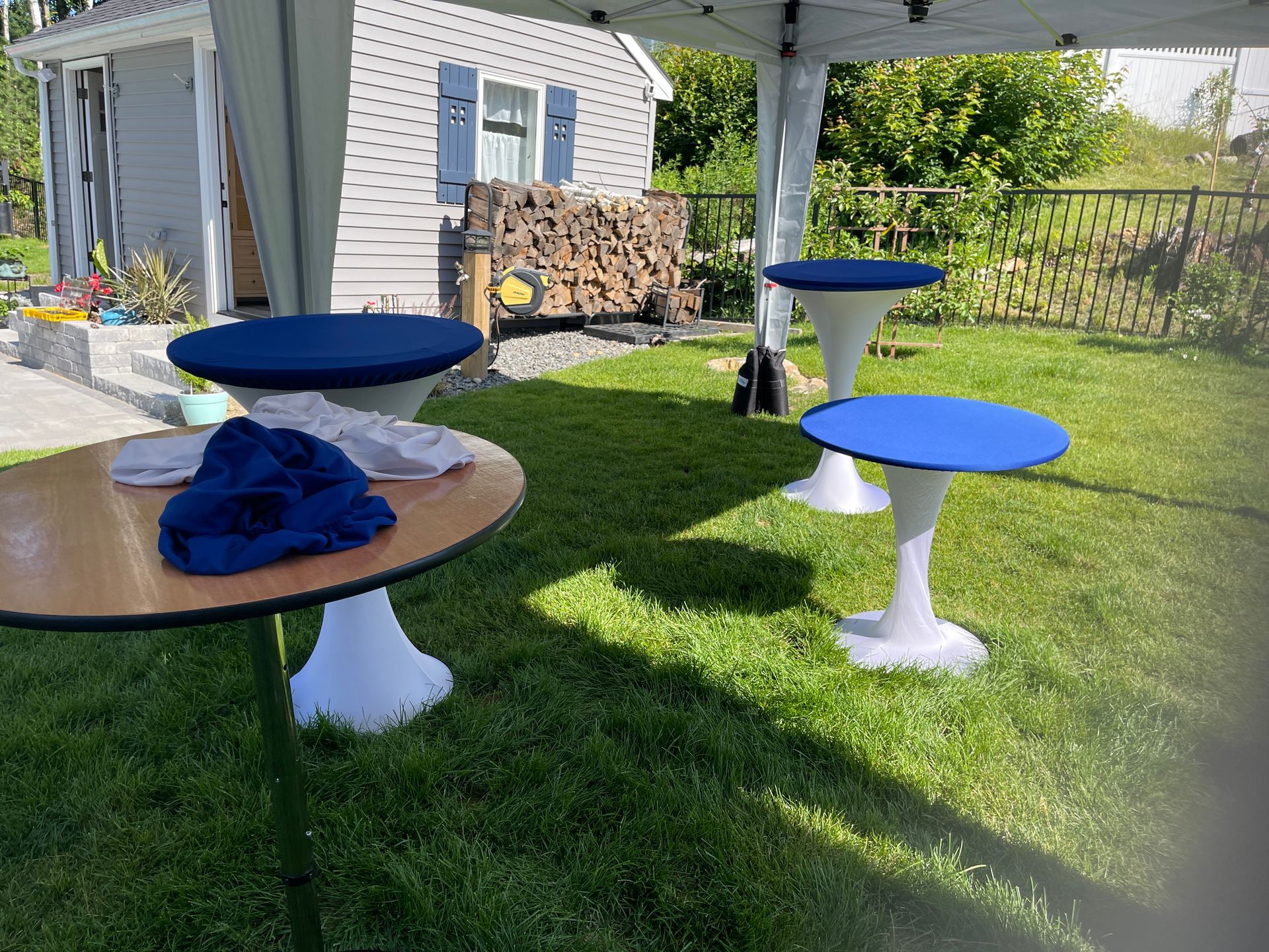 A group of tables are sitting in the grass under a tent.