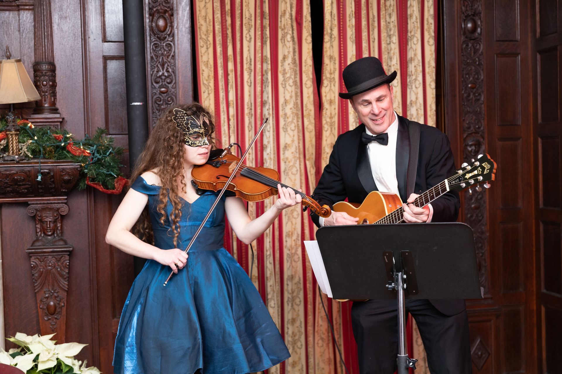 A woman is playing a violin and a man is playing a guitar.