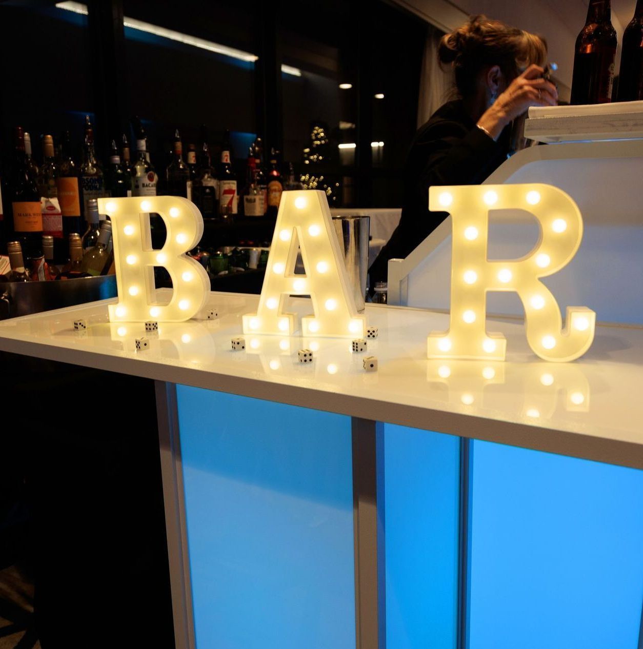 The word bar is lit up on a counter in a bar