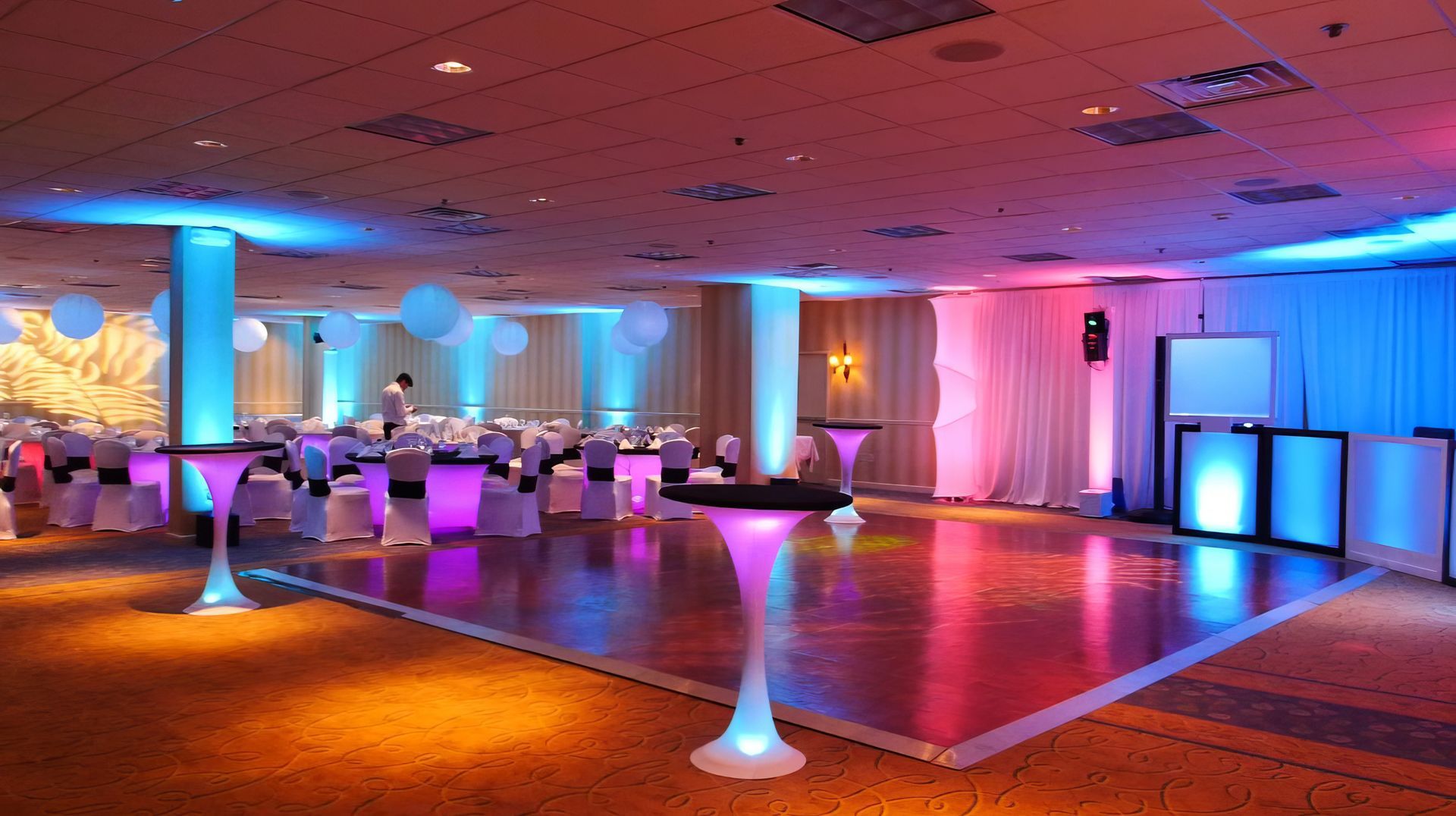 A large room with tables and chairs and a dance floor.