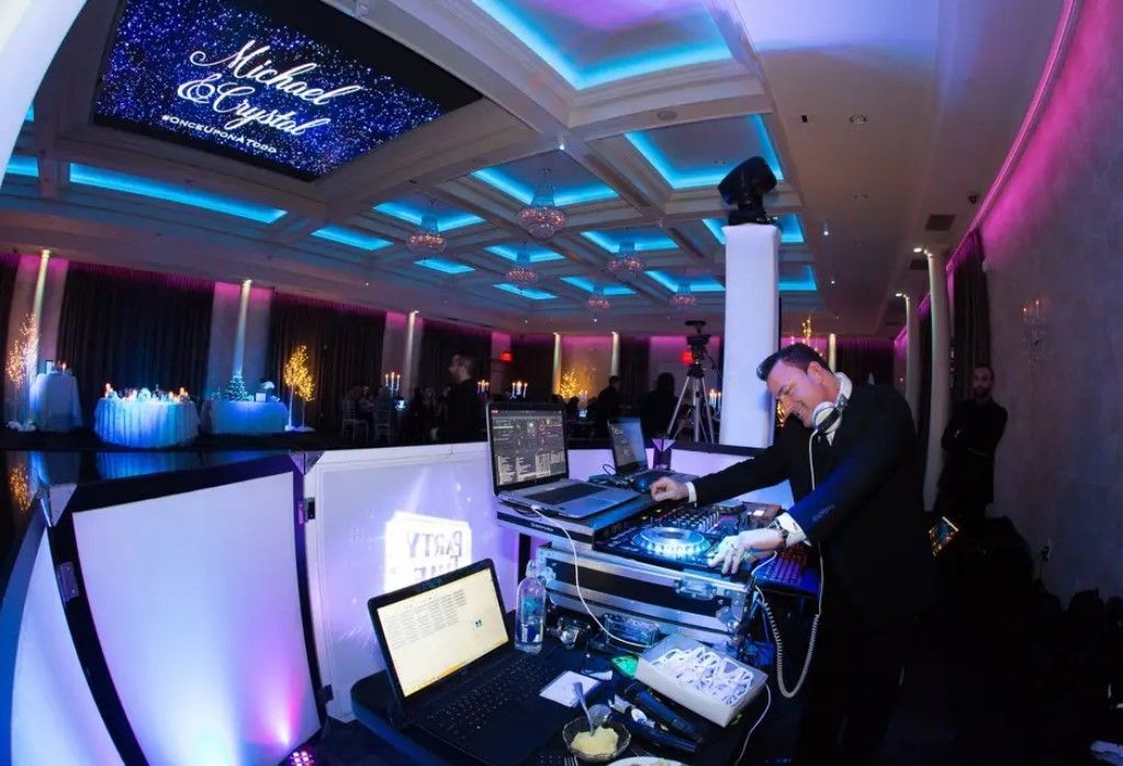 A dj is playing music at a party in a large room.
