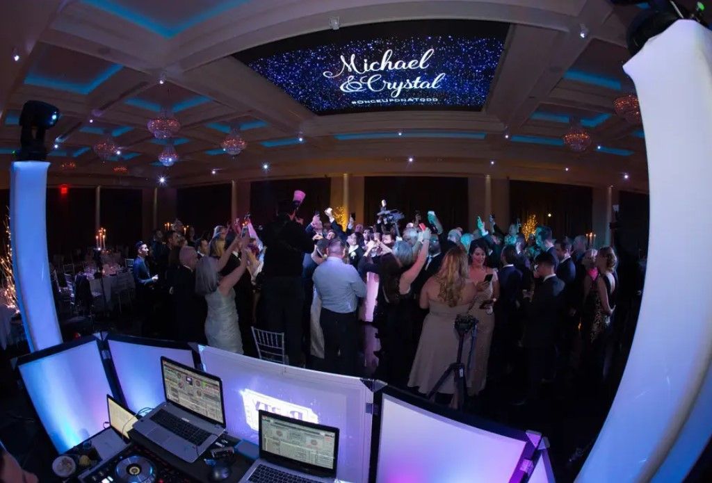 A large group of people are dancing at a wedding reception.