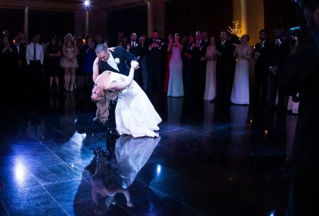 A bride and groom are dancing their first dance at a wedding reception.