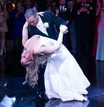 A bride and groom are dancing on a dance floor in front of a crowd.