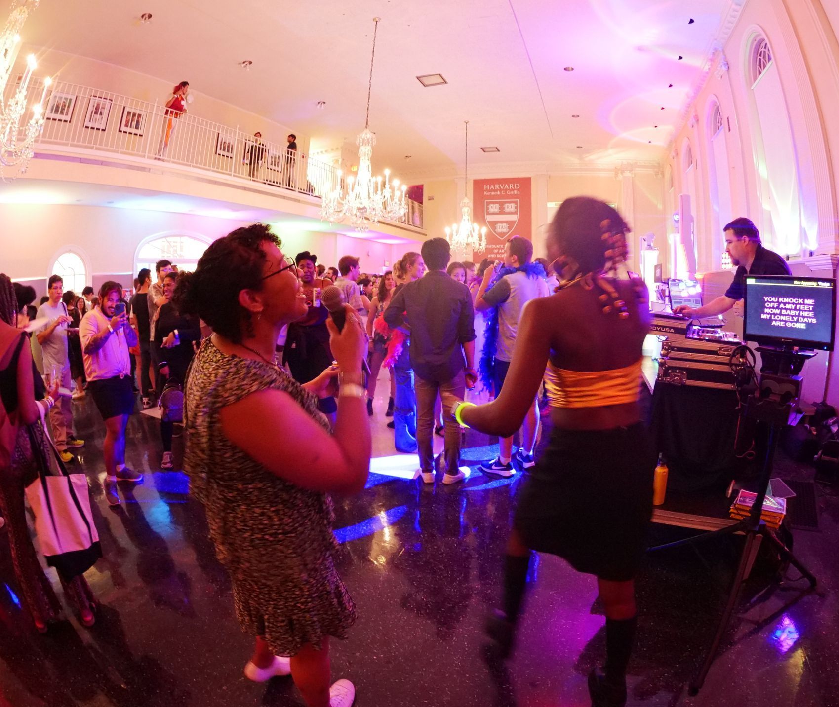 A group of people are dancing in a room with purple lights