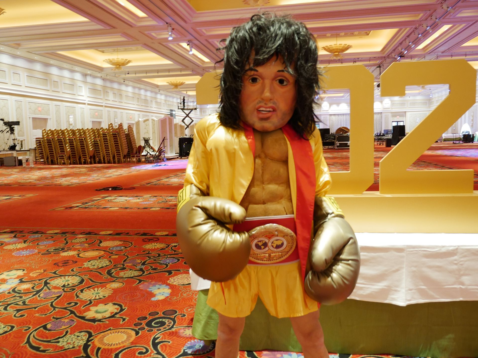 A man in boxing gloves is standing in front of a large number 12